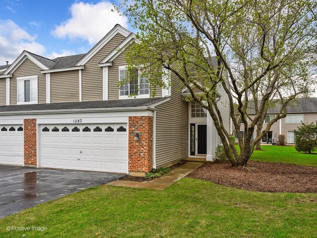view of front facade with brick siding, driveway, roof with shingles, a front lawn, and an attached garage