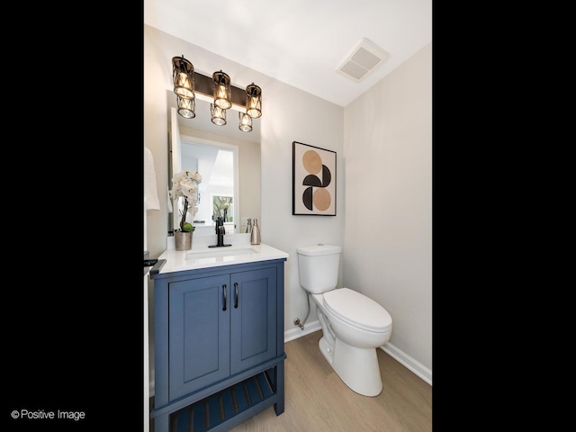 bathroom featuring vanity, toilet, visible vents, baseboards, and wood finished floors