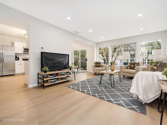 living area featuring recessed lighting, light wood-style flooring, and baseboards