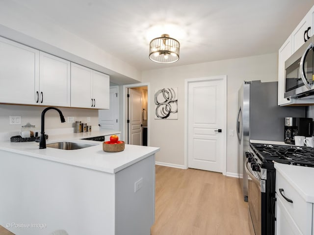 kitchen with white cabinets, light wood-style flooring, a sink, appliances with stainless steel finishes, and light countertops