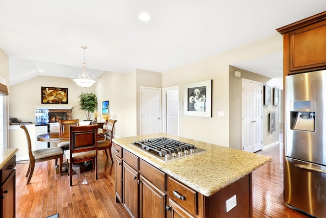35 Open Pkwy N, Hawthorn Woods, IL 60047 - kitchen with appliances with stainless steel finishes, hardwood / wood-style floors, light stone countertops, a brick fireplace, and vaulted ceiling