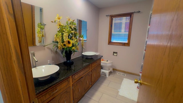 bathroom with toilet, double vanity, a sink, and visible vents