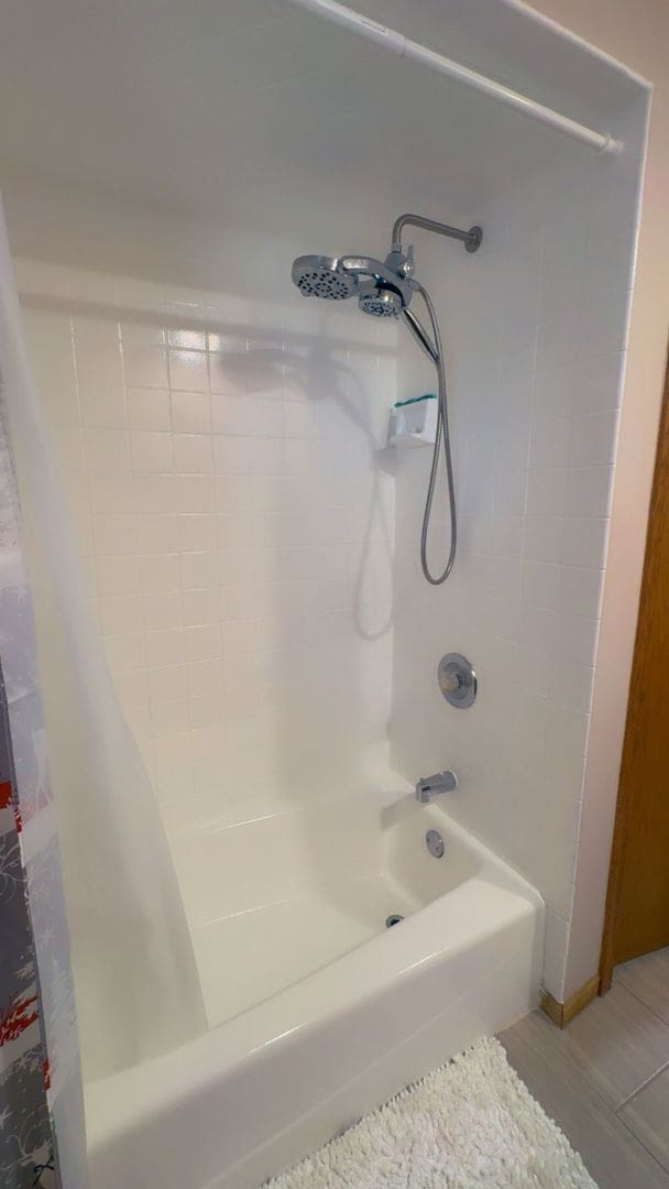 bathroom featuring shower / bathtub combination with curtain and wood finished floors