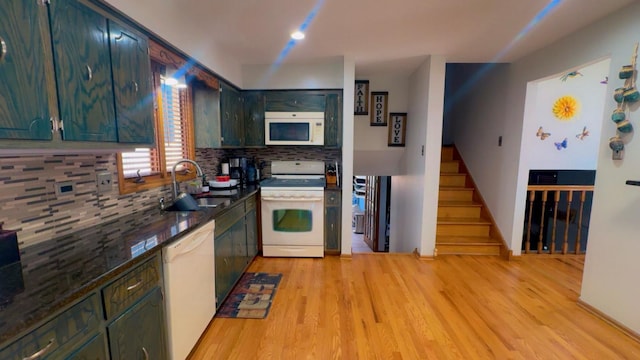 kitchen featuring light wood-type flooring, a sink, tasteful backsplash, and white appliances
