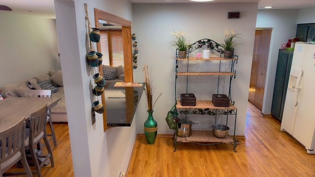 interior space featuring recessed lighting, white fridge with ice dispenser, and wood finished floors