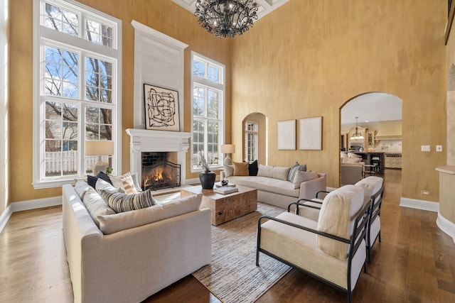 26W051 W Mohican Dr, Wheaton, IL 60189 - living room with wood finished floors, a towering ceiling, arched walkways, and a warm lit fireplace