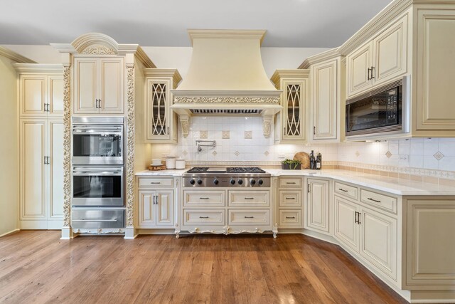 26W051 W Mohican Dr, Wheaton, IL 60189 - kitchen featuring light wood-style flooring, stainless steel appliances, premium range hood, cream cabinetry, and a warming drawer