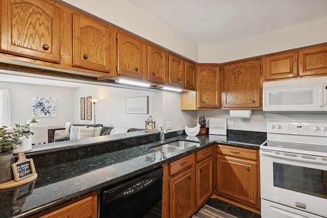 kitchen featuring a sink, dark stone counters, brown cabinets, and white appliances