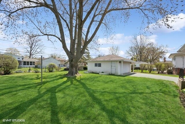 view of yard featuring an outdoor structure, driveway, and a detached garage