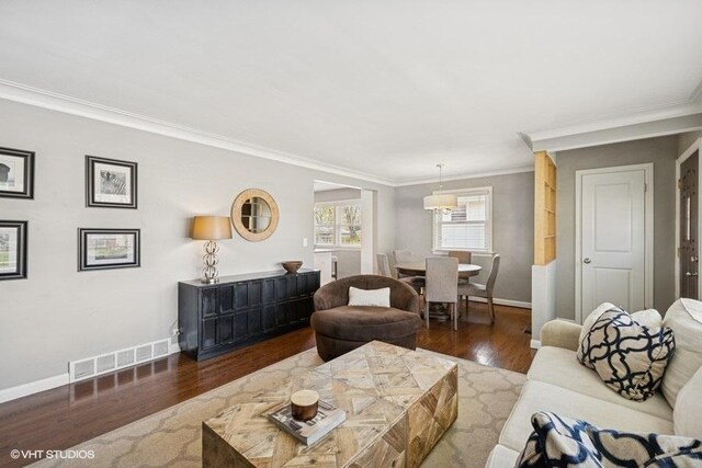 living area with crown molding, baseboards, visible vents, and wood finished floors
