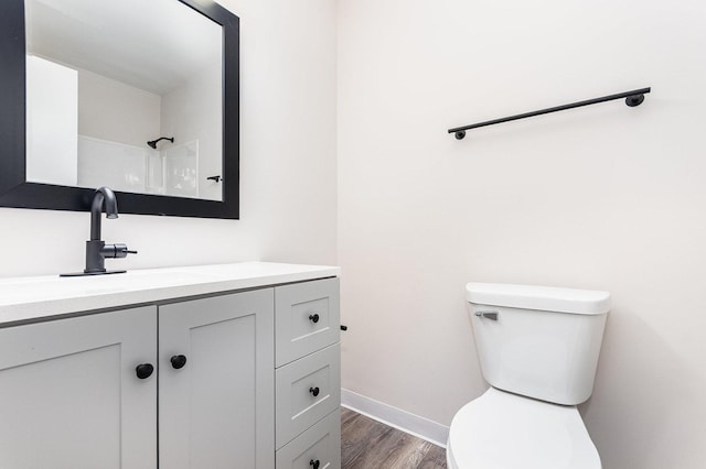 bathroom featuring toilet, wood finished floors, vanity, and baseboards