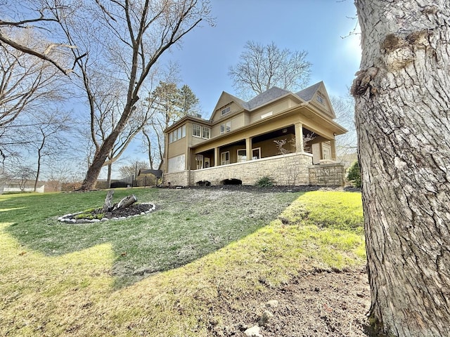 back of property featuring a lawn and stone siding