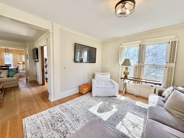 living room with ornamental molding, wood finished floors, and baseboards