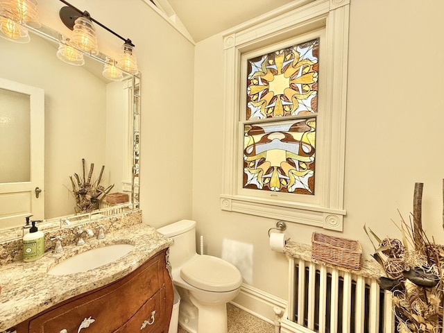 bathroom featuring lofted ceiling, baseboards, toilet, radiator heating unit, and vanity