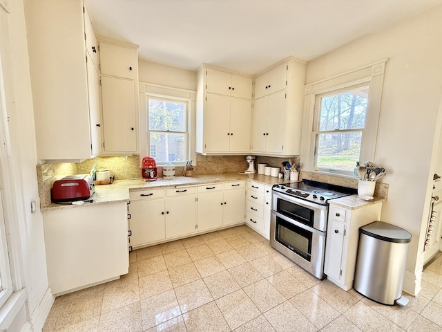 kitchen with range with two ovens, tasteful backsplash, granite finish floor, and light countertops