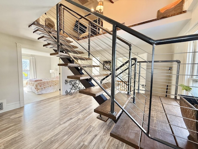 stairs with visible vents, wood finished floors, and baseboards