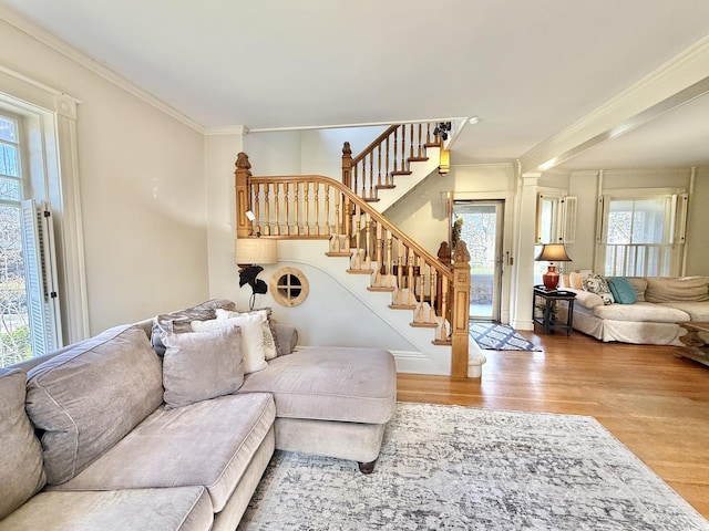 living area with ornamental molding, stairs, and wood finished floors