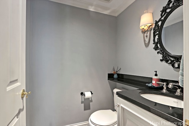 half bath featuring crown molding, vanity, and toilet