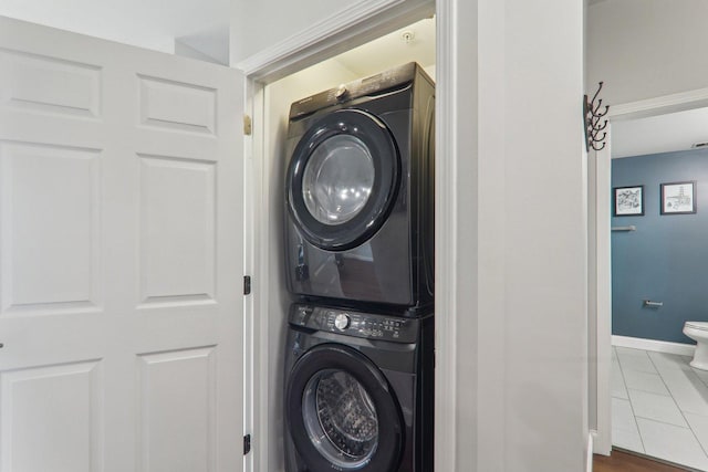 laundry area featuring baseboards, tile patterned flooring, stacked washer / drying machine, and laundry area