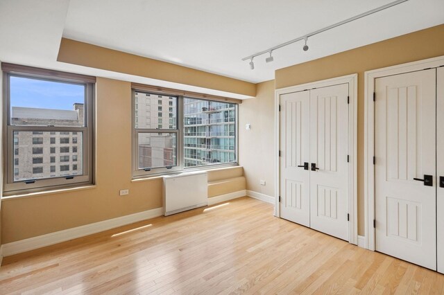 247 E Chestnut St Unit 2303, Chicago, IL 60611 - unfurnished bedroom with two closets, track lighting, multiple windows, and light wood-style floors