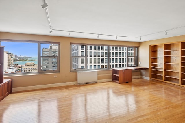 247 E Chestnut St Unit 2303, Chicago, IL 60611 - unfurnished living room featuring track lighting, light wood-type flooring, and baseboards