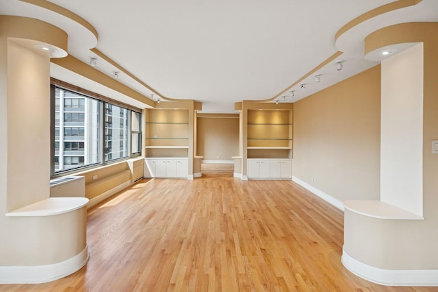 247 E Chestnut St Unit 2303, Chicago, IL 60611 - unfurnished living room featuring baseboards, light wood-style floors, and rail lighting