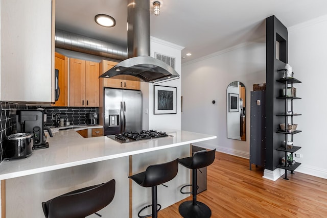 kitchen featuring appliances with stainless steel finishes, ornamental molding, a peninsula, and tasteful backsplash