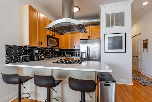 kitchen featuring light countertops, stainless steel appliances, a peninsula, island exhaust hood, and visible vents