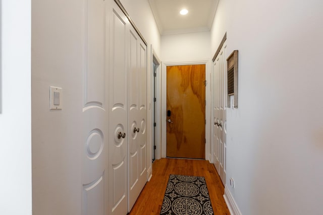 corridor with ornamental molding and light wood-style flooring