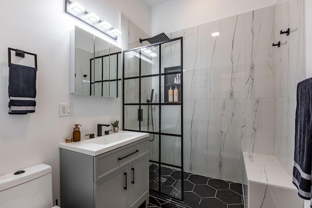 bathroom featuring a marble finish shower, vanity, and toilet