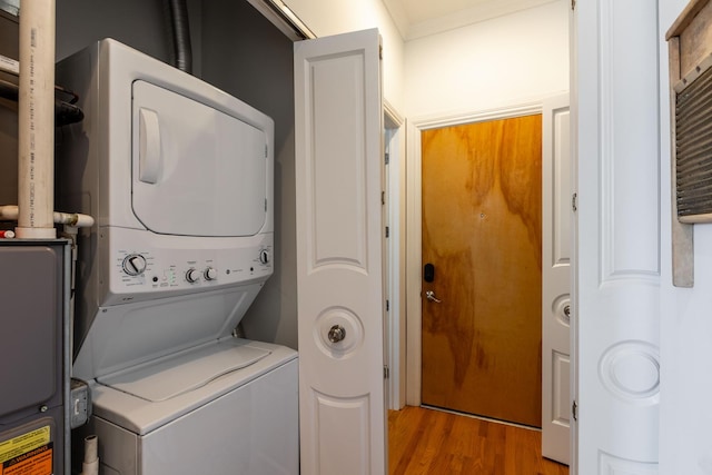 laundry area with laundry area, wood finished floors, and stacked washer and clothes dryer