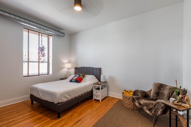 bedroom with baseboards, multiple windows, a ceiling fan, and light wood-type flooring