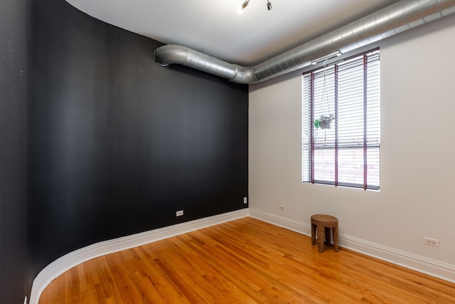 spare room with baseboards and wood finished floors