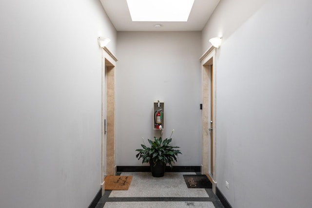 hallway featuring baseboards and a skylight