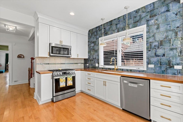 1833 Asbury Ave, Evanston, IL 60201 - kitchen featuring a sink, wood counters, tasteful backsplash, white cabinets, and appliances with stainless steel finishes
