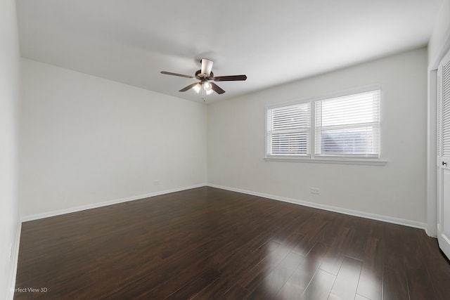 empty room featuring dark wood-type flooring, a ceiling fan, and baseboards