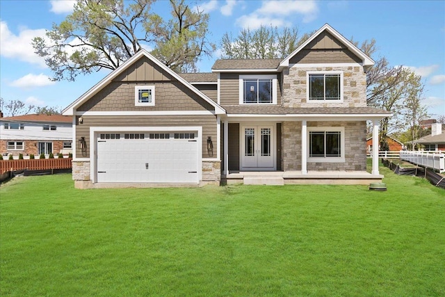 view of front of house with a front yard, stone siding, a garage, and fence