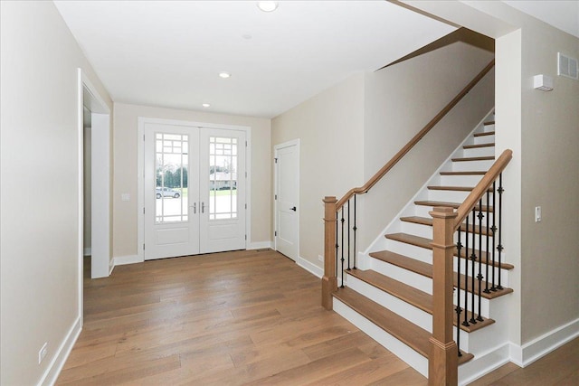 foyer entrance featuring wood finished floors, french doors, recessed lighting, and stairs