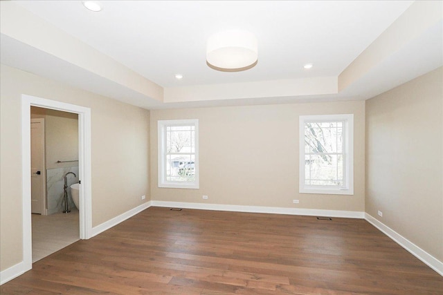 unfurnished room featuring baseboards, recessed lighting, dark wood-type flooring, and a tray ceiling