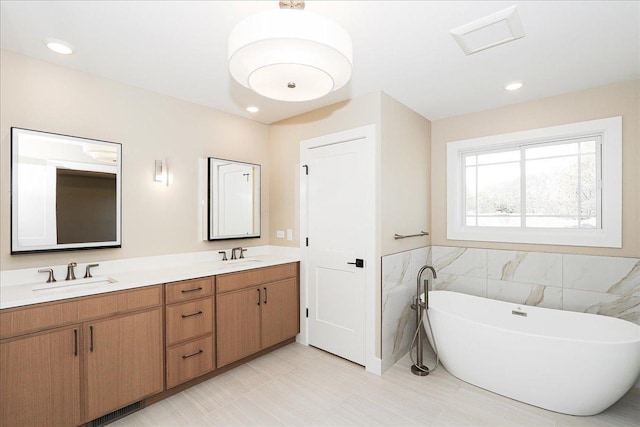 full bathroom featuring double vanity, tile walls, a soaking tub, and a sink