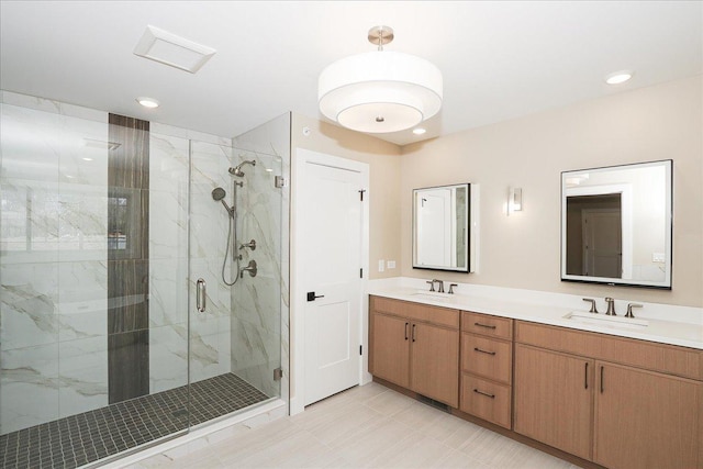 full bath with a marble finish shower, a sink, and double vanity