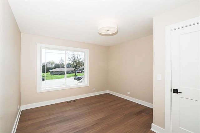 unfurnished room featuring visible vents, baseboards, and dark wood-type flooring