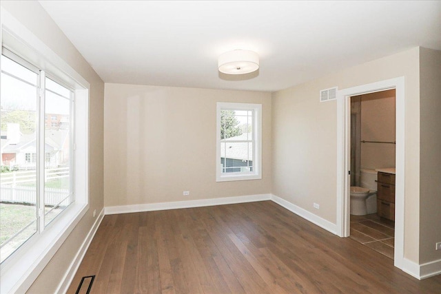 empty room featuring baseboards, visible vents, and dark wood-type flooring