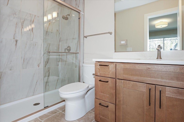 bathroom with tile patterned floors, a marble finish shower, toilet, and vanity