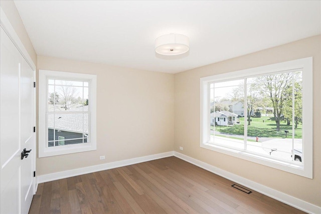 empty room with visible vents, wood finished floors, and plenty of natural light