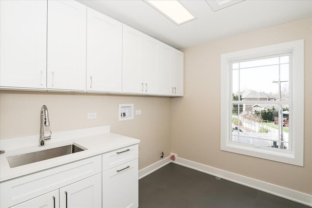 laundry area featuring cabinet space, hookup for a gas dryer, washer hookup, a sink, and baseboards