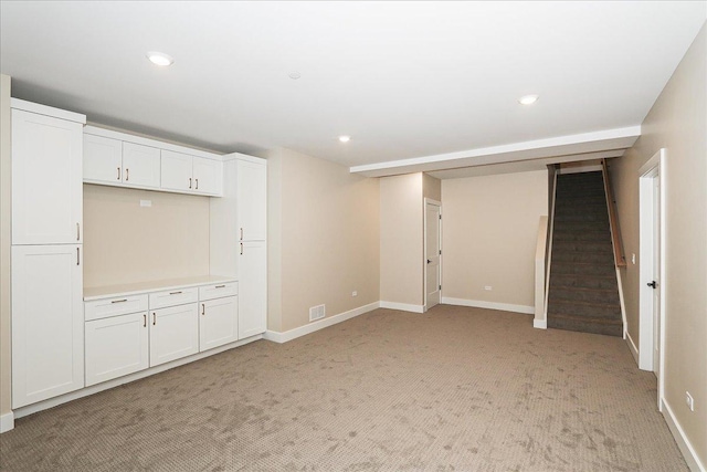below grade area with light colored carpet, baseboards, recessed lighting, and stairs