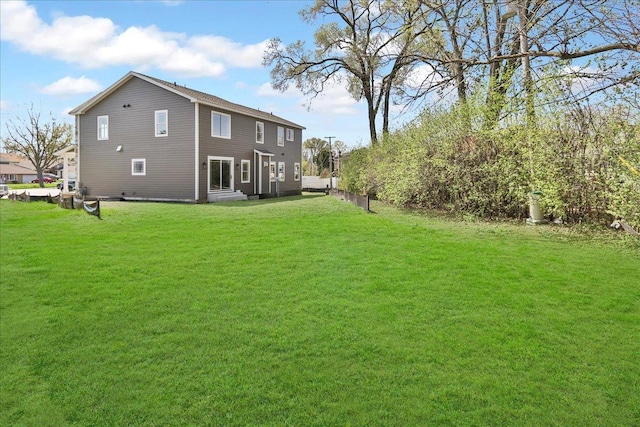 back of property with fence and a lawn