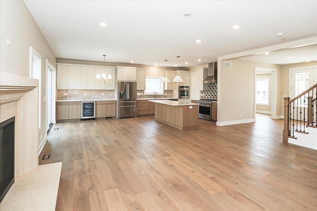 kitchen with decorative backsplash, stainless steel appliances, a center island, wall chimney exhaust hood, and wine cooler