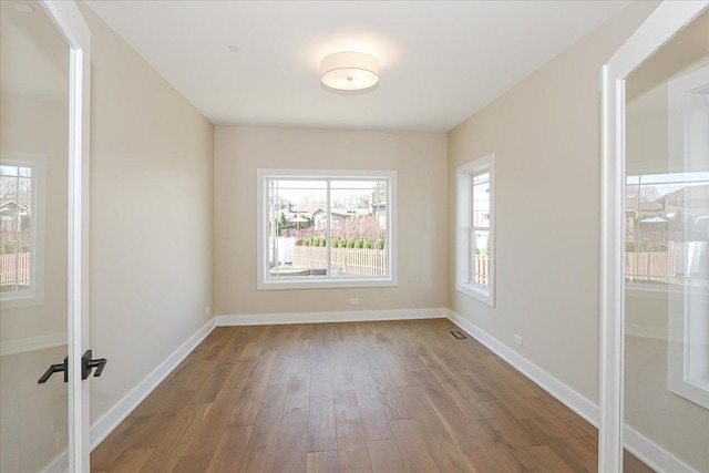 unfurnished room featuring visible vents, french doors, wood finished floors, and baseboards